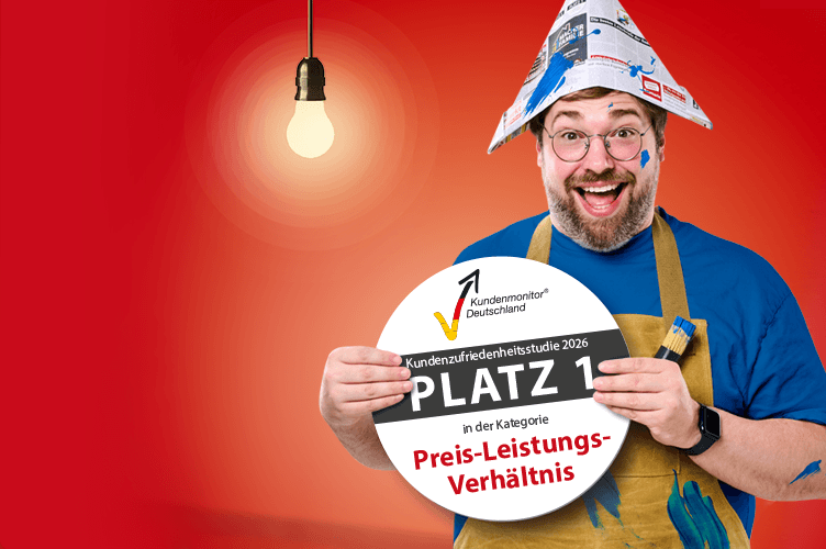 Mann mit farbverschmiertem Gesicht und brauner Malerschürze hält ein rundes Siegel vom Kundenmonitor 2026 in den Händen